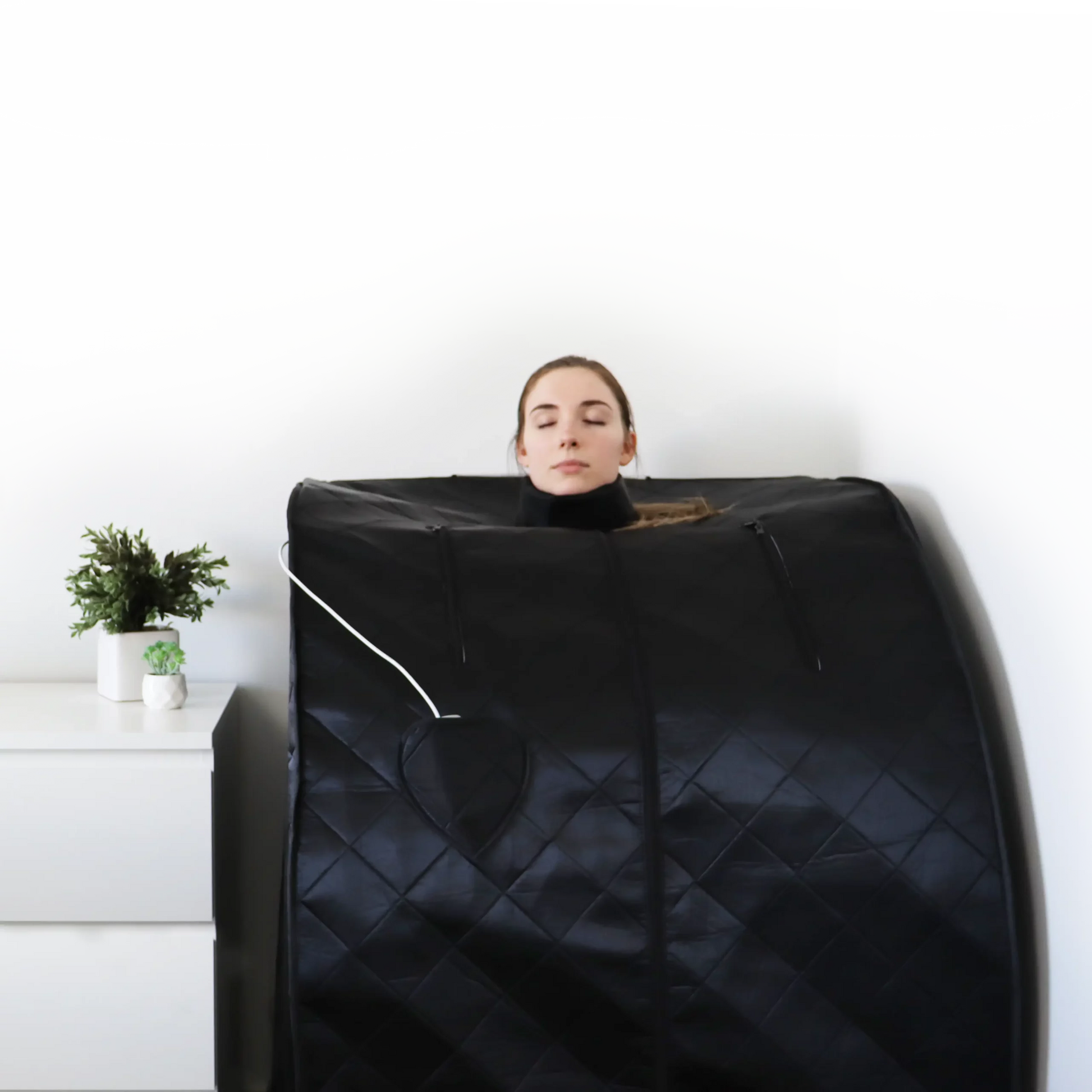 A woman looks very relaxed as she uses the UltraLux Foldaway Sauna